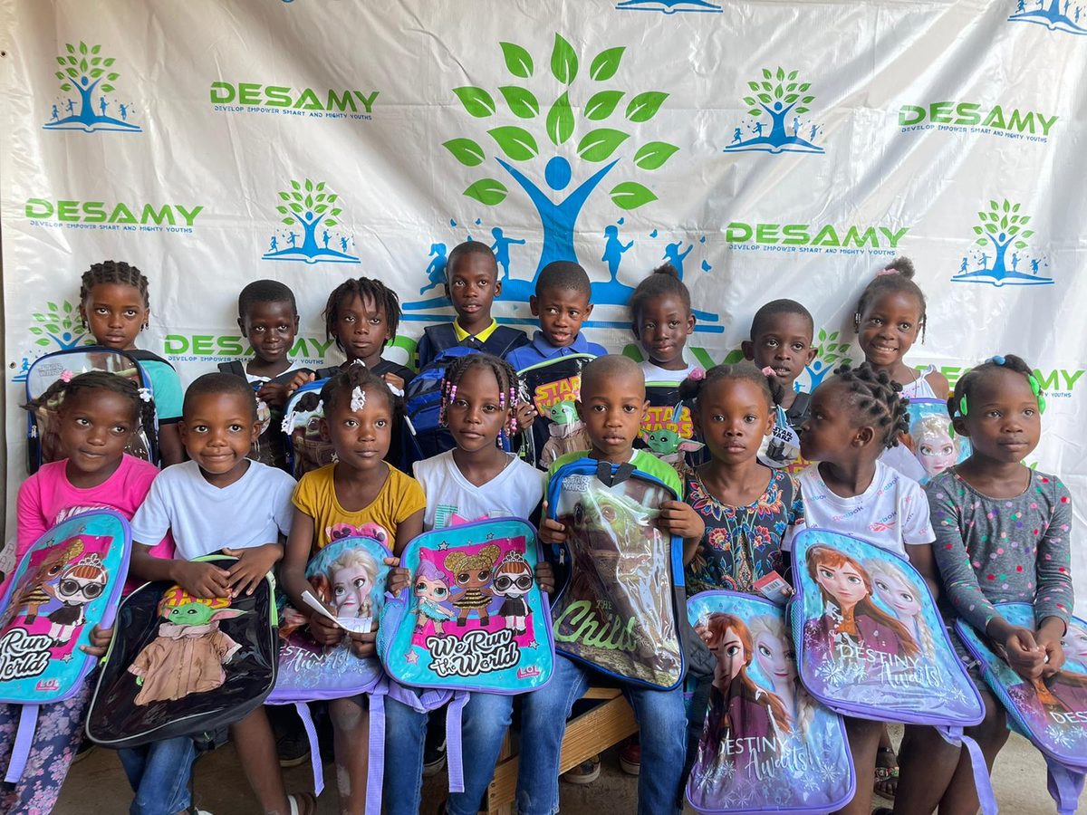 Young students showing their new backpacks at a DESAMY back-to-school event